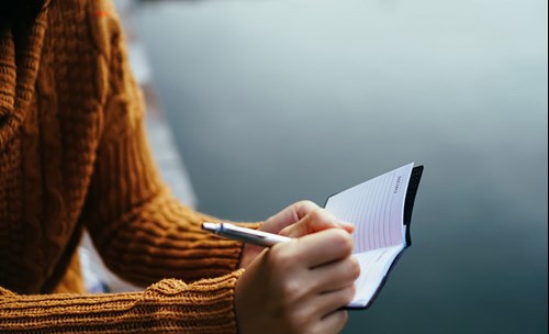 Person writing in small notebook