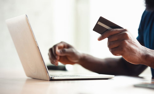 Person using laptop with bank card in his hand