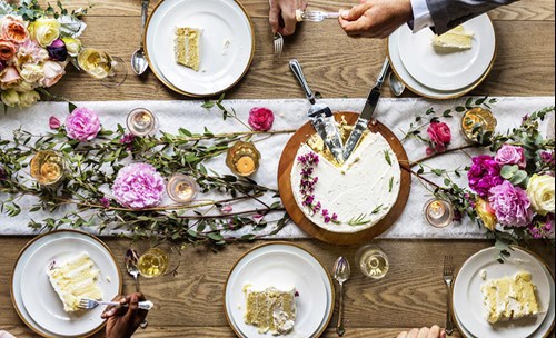 Wedding cake slices on plates, on a decorated table with flowers