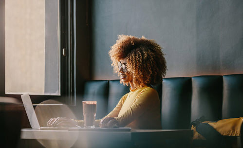 Woman in cafe using laptop and smiling