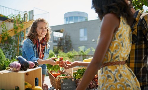 Woman buying fresh produce from a stall at a farmers market