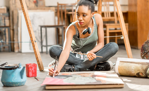 Woman sitting on the floor, painting on canvas