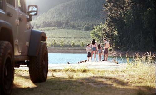 Family of four on dock of a dam, in nature, trees and mountain around them